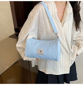 Detail of light blue canvas cylinder bag with cute puppy patch on a striped shirt