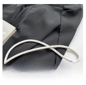 Detail view of the white woven texture shoulder strap on a stylish crossbody phone bag