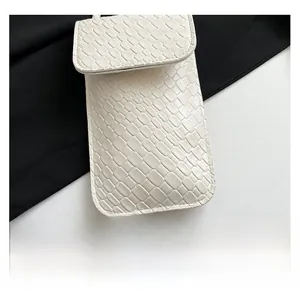 Close-up of white crocodile pattern faux leather texture on minimalist crossbody phone bag