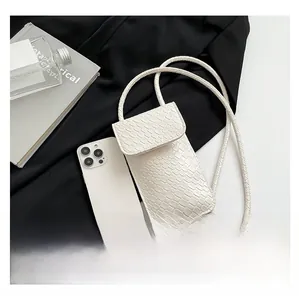 Detail of white crocodile pattern phone bag with magnetic flap and slim strap