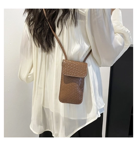Detailed view of a brown woven texture crossbody phone bag on a minimalist white outfit
