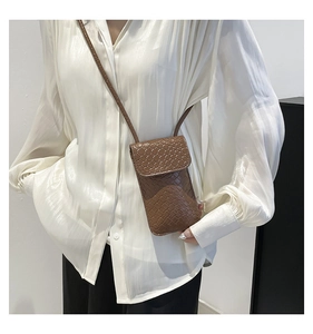 Detail of a brown woven texture crossbody phone bag with a stylish flap and slender strap