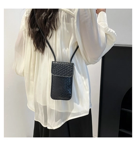 Detail of crossbody phone bag in black woven leather texture on a female model