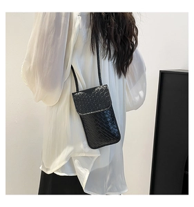 Detail of black woven texture crossbody phone bag with flap closure and slim shoulder strap