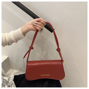 Detail of red crocodile texture small square bag with golden knot strap accents