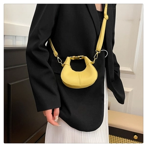 Detail of yellow crescent mini crossbody bag with golden chain and sleek leather finish