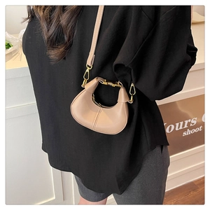 Detail of a mini crescent bag in khaki faux leather with elegant gold metal hardware