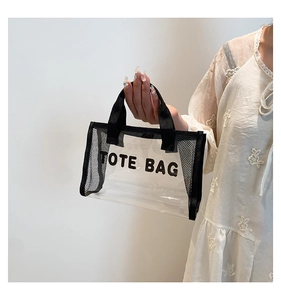 Detail of transparent PVC tote bag with black mesh side panels and TOTE BAG lettering