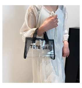 Detail of transparent PVC tote bag with black mesh handle and TOTE BAG lettering