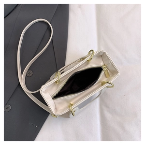 Dettaglio della borsa in pelle PU bianco crema con manico ad anello dorato e zip