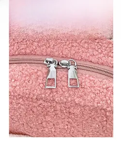Detail view of pink fleece bag showing dual silver metal zippers and textured fabric