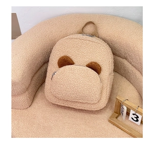 Detail of plush bear-ear backpack showing lamb wool texture and front zipper pocket