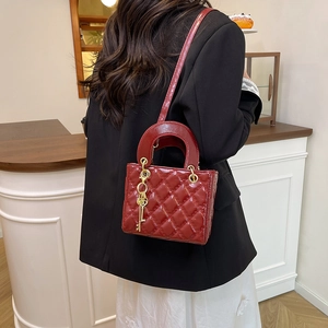 Borsa in pelle trapuntata rossa con ciondolo chiave dorato indossata da una modella