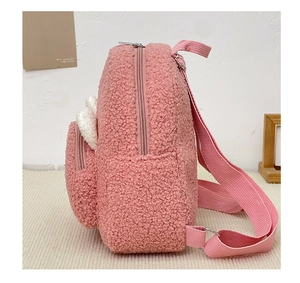 Detail of pink faux shearling backpack featuring plush white wings and ribbon straps