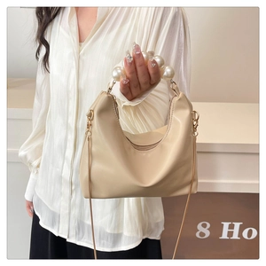 Detail of hobo bag with large pearl handle and gold chain strap in cream finish