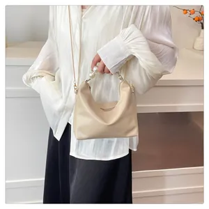 Detail of beige leather crossbody bag with large pearl handle and gold chain strap