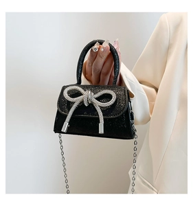 Detail of black glitter crossbody bag featuring a sparkling silver rhinestone bow decoration