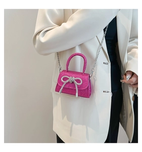 Détail du mini sac rose pailleté avec nœud argenté et bandoulière sur veste blanche