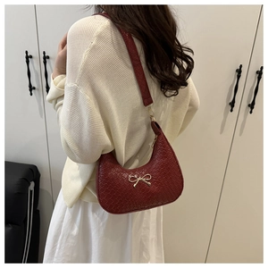 Model wearing red woven hobo bag with gold bow clasp showing shoulder carrying effect