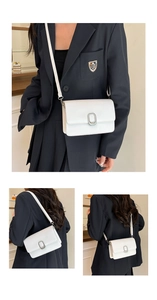 Detail view of white faux leather crossbody bag with silver oval metal buckle and thin strap