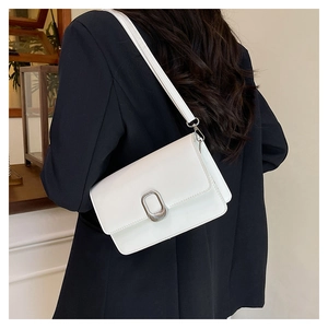 Detail of white minimalist crossbody bag with silver oval buckle on a black blazer