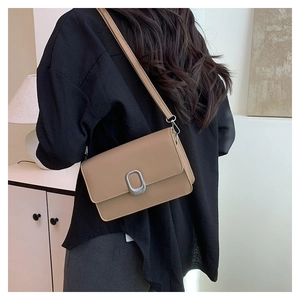 Detail view of khaki square shoulder bag with silver oval metal buckle on crossbody strap
