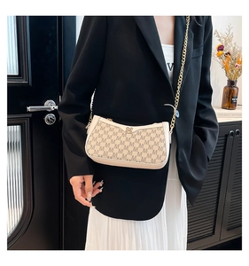 Detail of vintage beige monogram crossbody bag with gold chain strap on female model