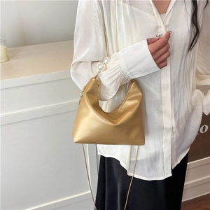 Champagne gold pearl handle Hobo bag with chain strap shown on a model in minimalist style