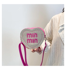 Detail view of heart-shaped woven crossbody bag with pink leather trim and logo embroidery