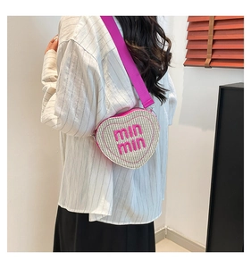 Detail of heart-shaped woven straw bag with pink min min embroidery and wide shoulder strap