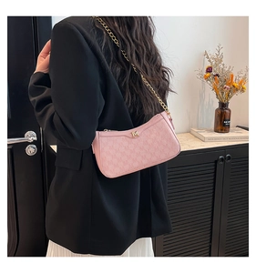 Detail of pink monogram underarm bag with gold M logo and elegant chain strap on shoulder