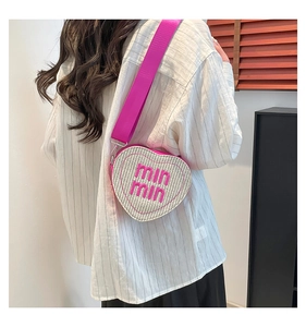 Detail of heart-shaped woven crossbody bag featuring pink trim and min min lettering