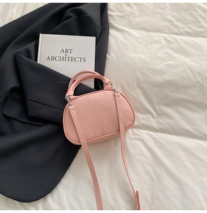 Dettaglio borsa rosa stampa coccodrillo con finiture argento su sfondo di tessuto