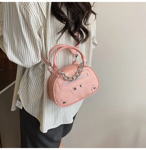 Detailed side view of pink mini shell bag with croc texture and silver chain