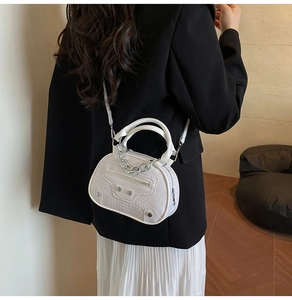 Detail of white crocodile pattern handbag with silver chain and vintage studs