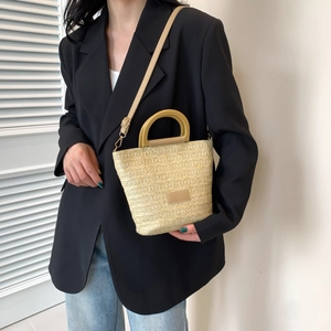 Minimalist beige woven handbag with resin handle and leather strap on a model