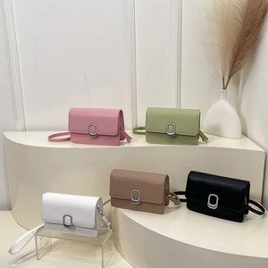 Minimalist square crossbody bags in five colors displayed on white curved pedestals