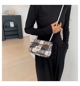Detail of plaid denim crossbody bag with silver metal chain strap and twist-lock closure