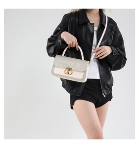 Detail view of stylish crossbody bag with gold round clasp and glitter texture