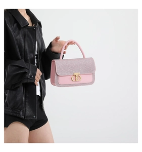 Detail of pink sequin texture and golden metal interlocking buckle on handbag