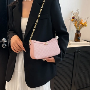 Pink monogram shoulder bag with gold chain strap worn by a model in a stylish suit