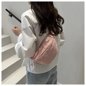 Vue détaillée d'un sac banane rose à carreaux porté en bandoulière par un mannequin