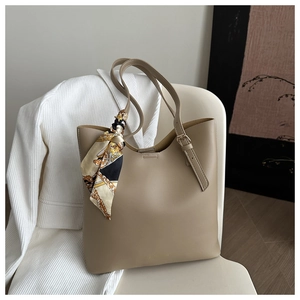 Détail du sac cabas en cuir kaki avec un foulard décoratif élégant sur la chaise