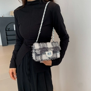 Fashionable tweed plaid shoulder bag with fringe trim and leather chain strap shown on model