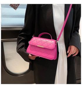 Detail of fuchsia quilted crossbody bag with gold metal buckle and leather handle