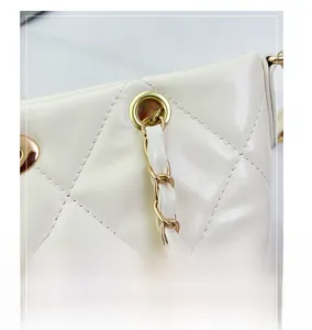 Dettaglio borsa trapuntata color crema con catena intrecciata e fibbie d'oro