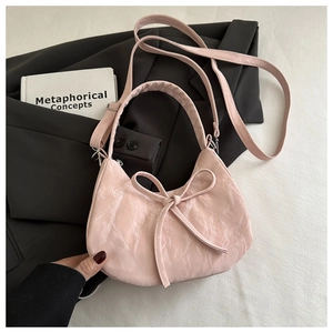 Pink bow handbag with pleated texture displayed on a black blazer for a stylish look