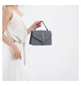 Détail du sac à main gris foncé avec texture tissée et boucle en métal doré chic