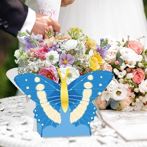 Blue butterfly paper favor box with yellow accents displayed in a romantic wedding setting
