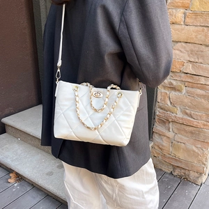 Borsa trapuntata bianca con tracolla a catena dorata indossata da modella su scale urbane